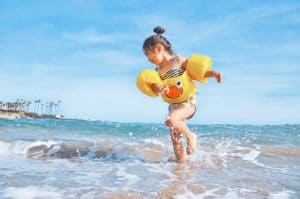 Child in rubber duck floaties playing at the beach creating generative change